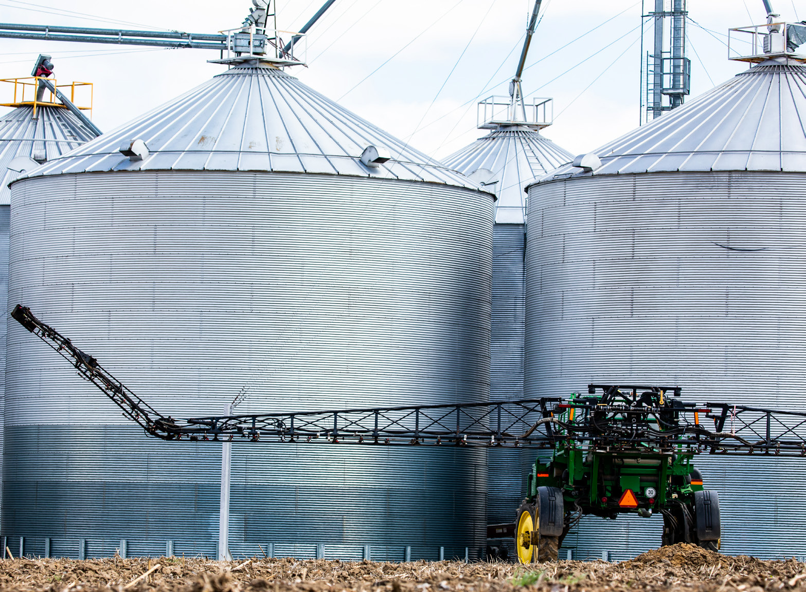 View of tractor next to large grain bins