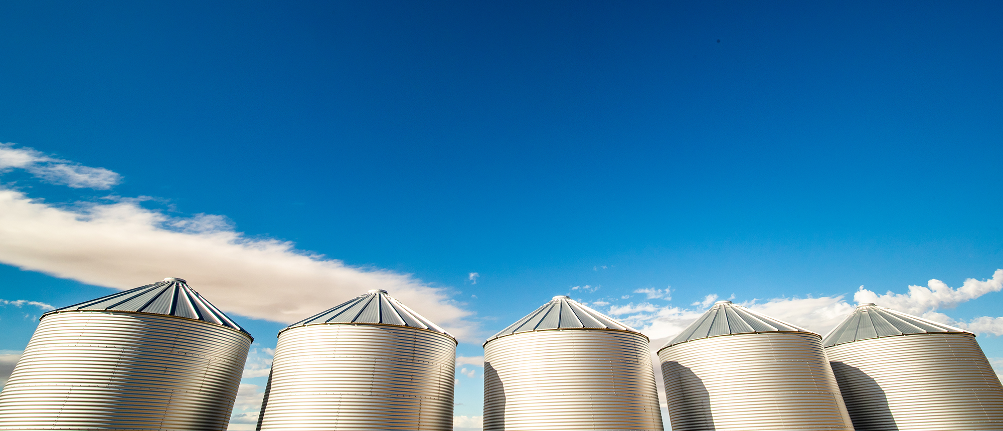 Grain bins against a bright blue sky