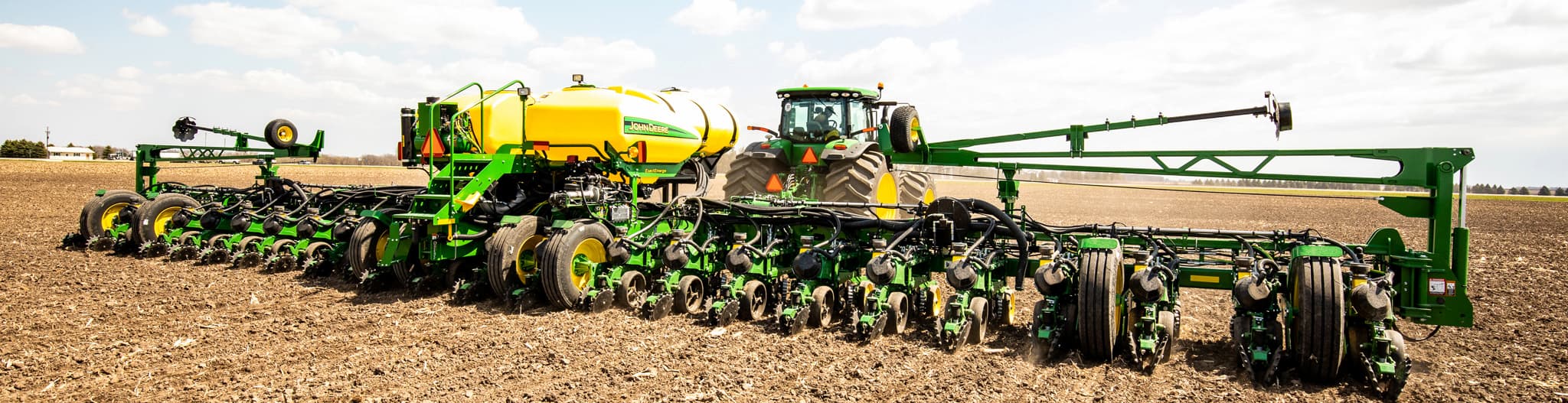 Tractor pulling seed planter through a dirt field