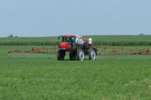 Crop sprayer driving through a grassy field