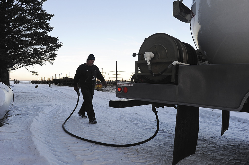 Man walking hose back to propane truck in winter